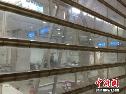 海龙电子城1楼，透过闸门，可以看到有人在整理现场。中新网 吴涛 摄